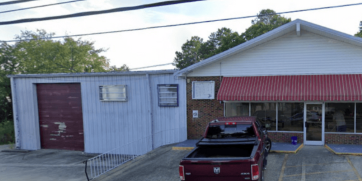 worn-down commercial building with faded blue siding/red awning the exterior looks aged 