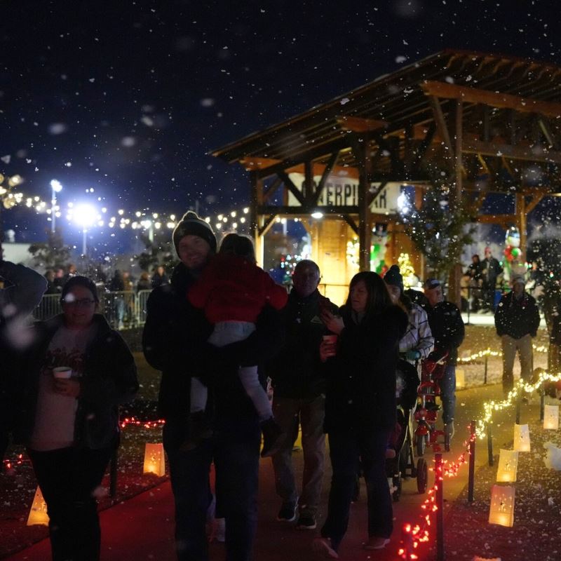 Families hold hot cocoa and smile while walking through Merry Municipal light show 