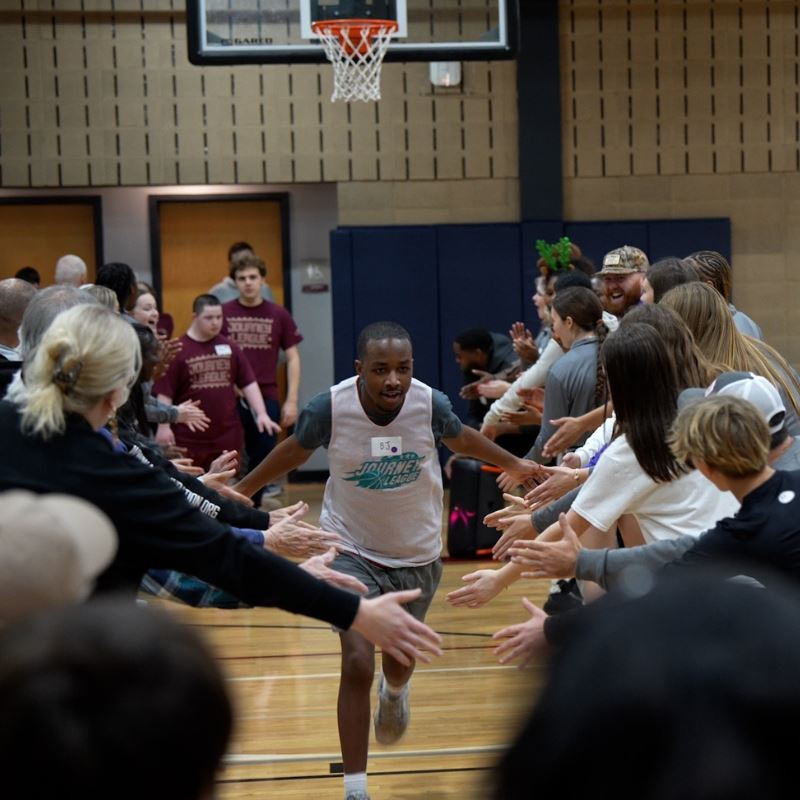 young man on basketball court runs through crowd giving high fives
