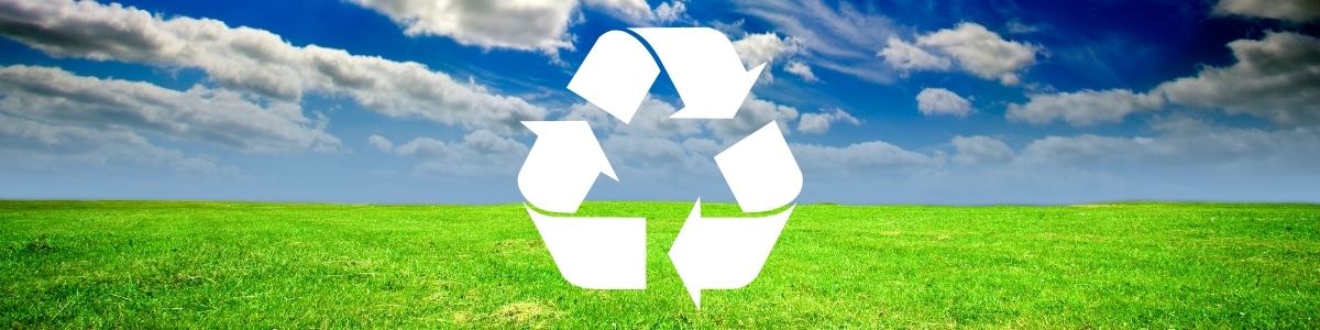 open field of green grass with cloudy blue sky and recycle symbol